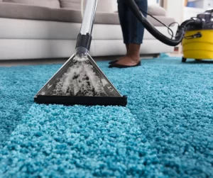 Someone using a carpet cleaner to clean their blue carpet.