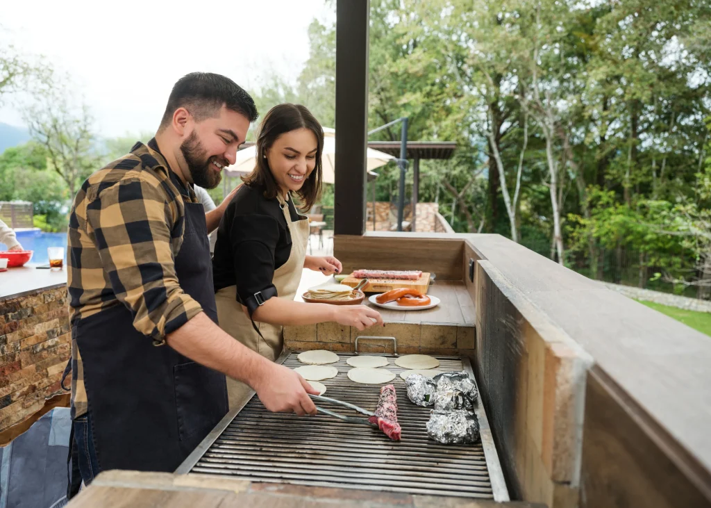 Couple using outdoor grill together in outdoor grilling area