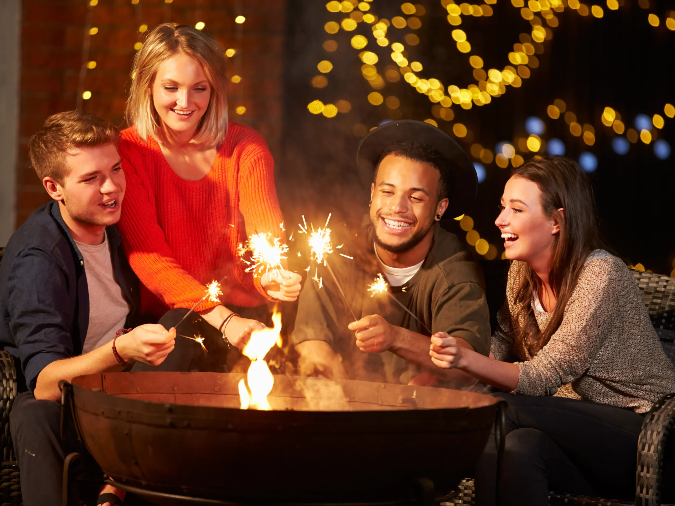 people holding sparklers over the firepit at a bonfire bash