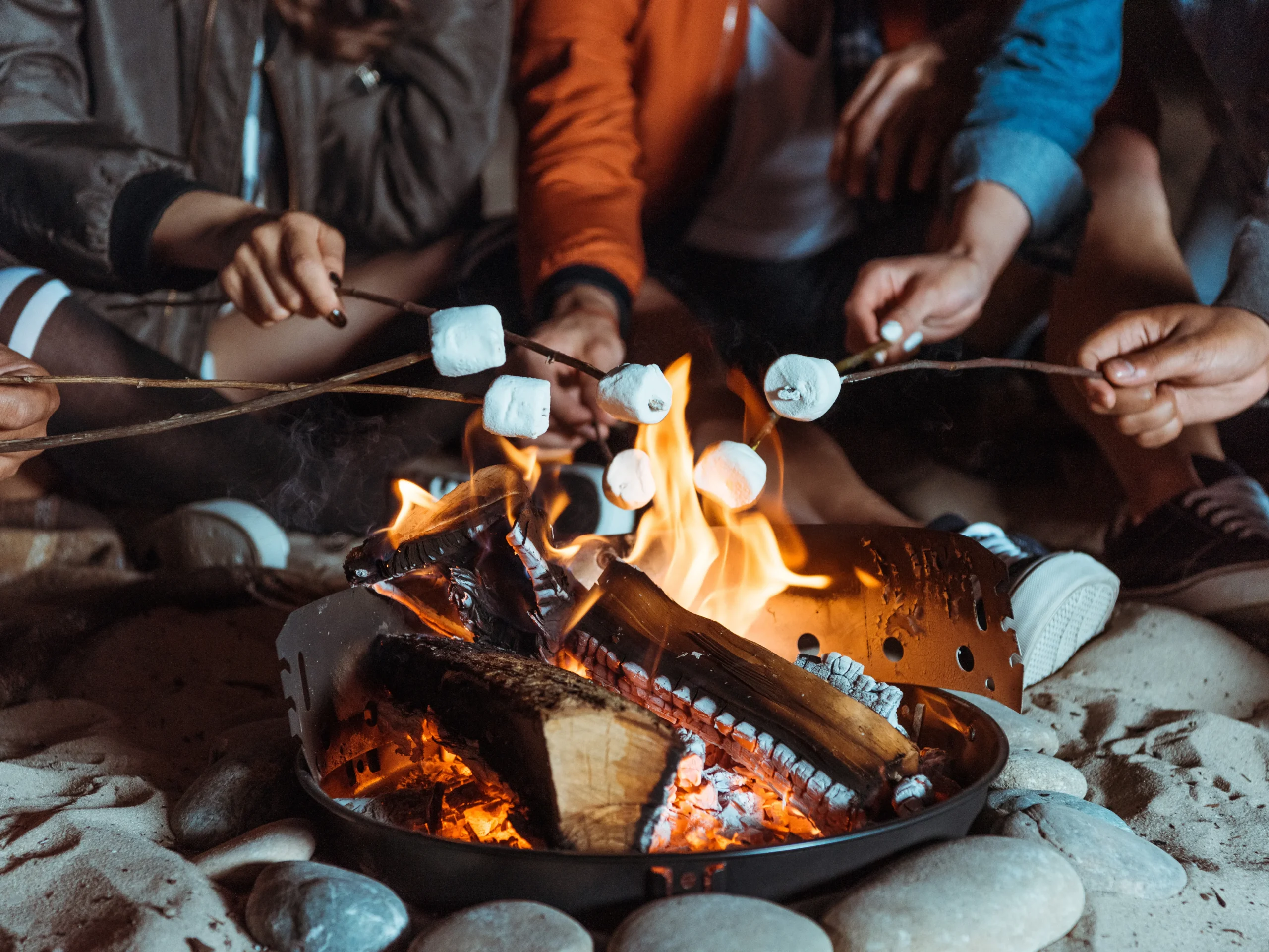 people roasting s'mores over fire pit at bonfire bash