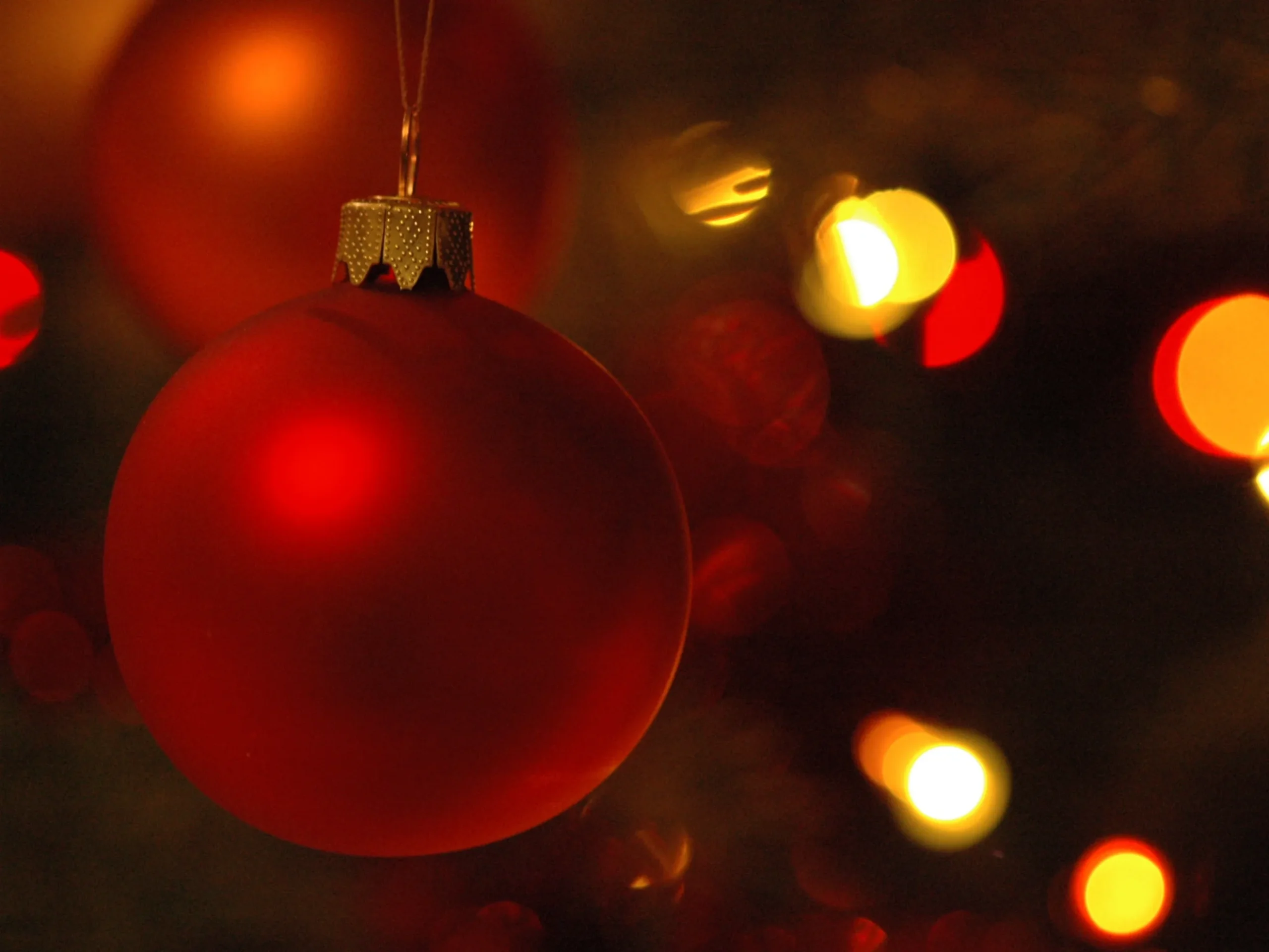 red ornament in front of Christmas lights